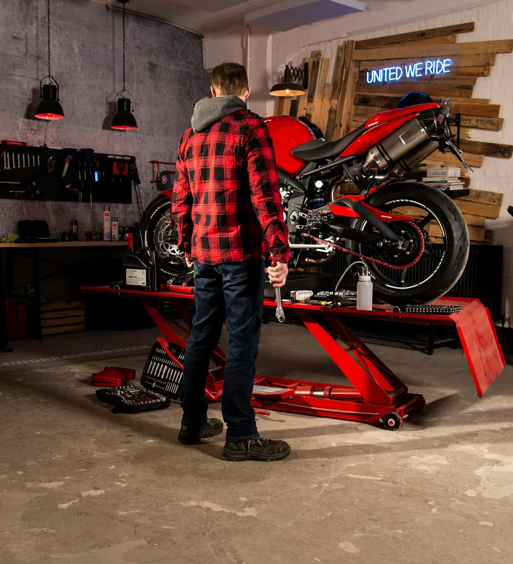 Motocicleta roja sobre una plataforma de mantenimiento en un taller